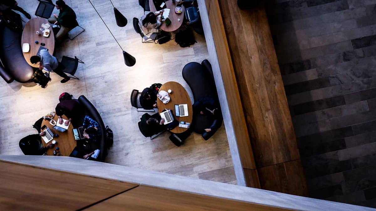 aerial photo of 4 tables full of students and laptops